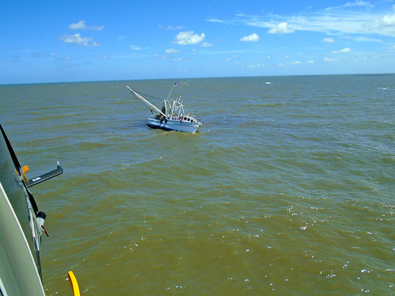 Responders aboard a Coast Guard Air Station Savannah MH-65 Dolphin helicopter approach the Lady Vanessa, which began taking on water May 18, 2017, near St. Simons Island, Ga. Three fishermen were rescued safely. USCG photo.