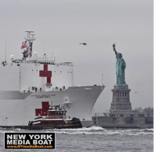 The hospital ship Comfort with the tug Capt. Brian A. McAllister on the starboard bow passes the Statue of Liberty March 30, 2020. Bjoern Kils/New York Media Boat photo.